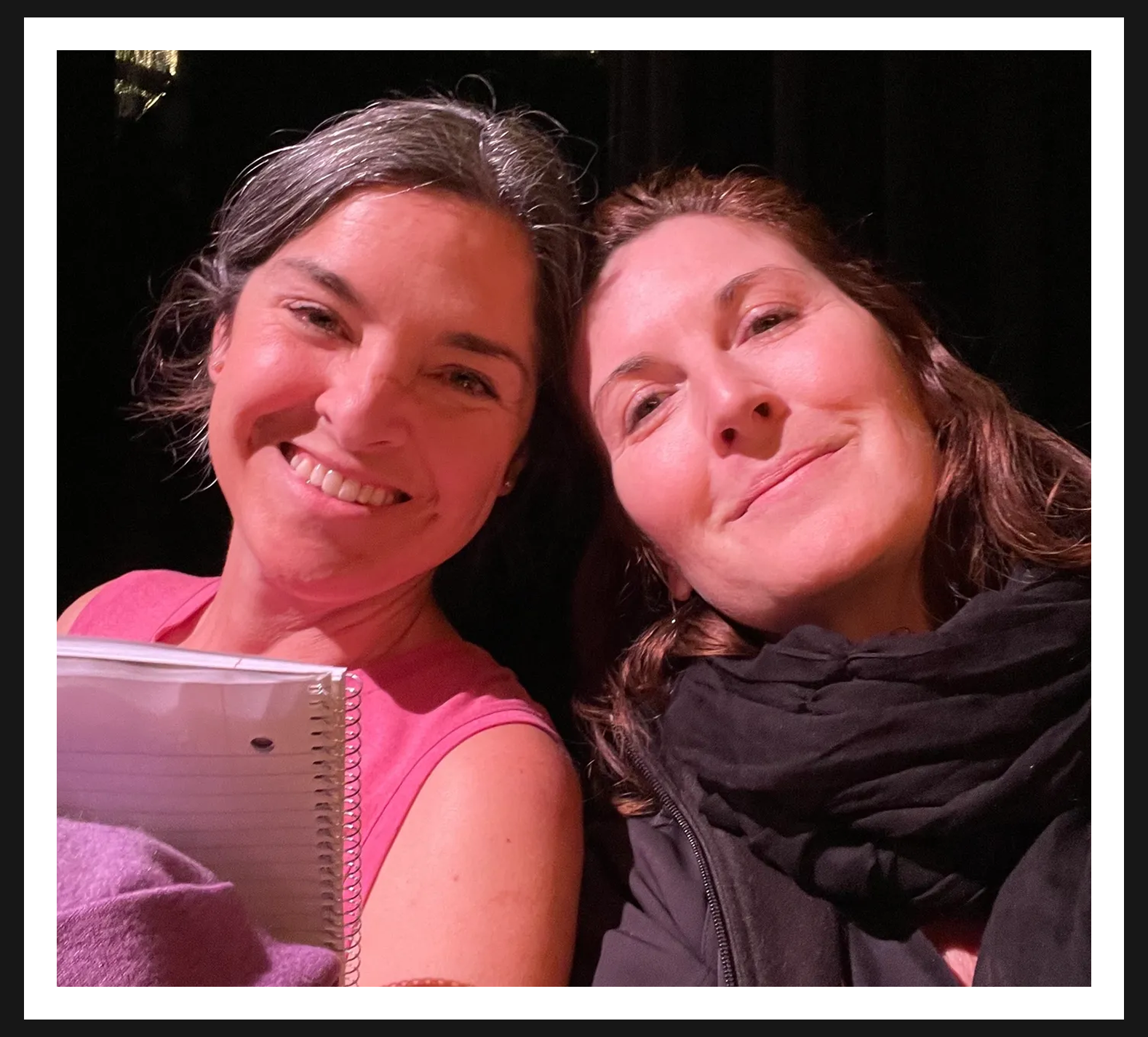 Two women smiling with a notebook
