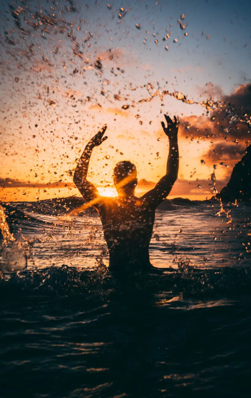 Person enjoying ocean waves at sunset