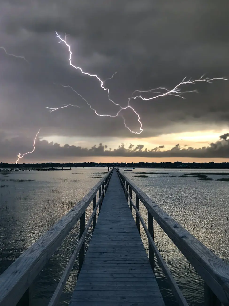 Lightning over wooden pier at sunset