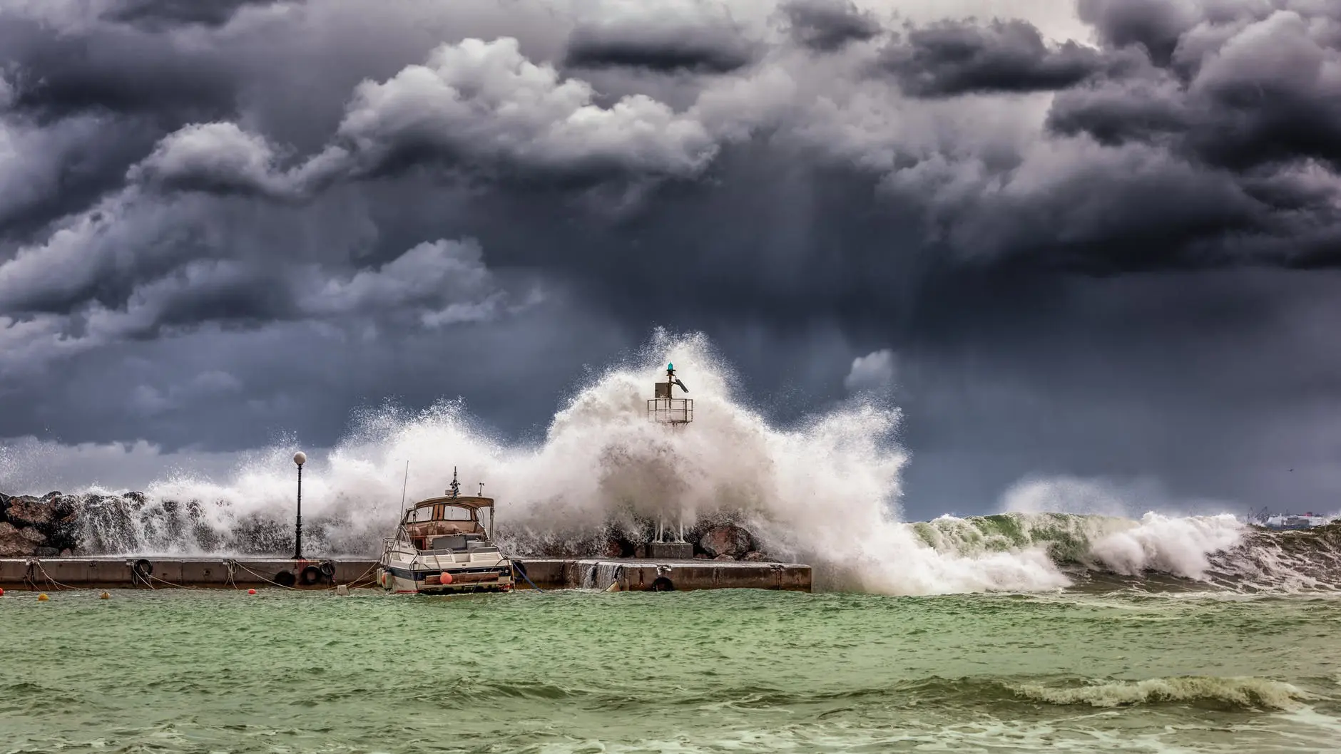Stormy waves crashing against lighthouse pier