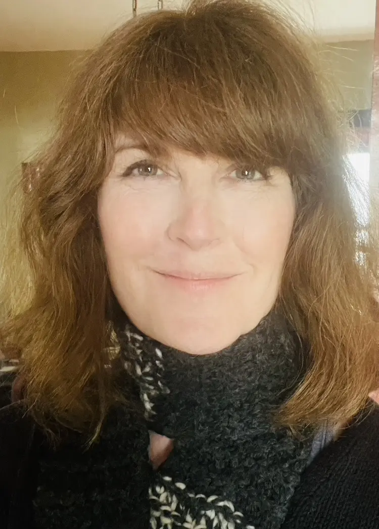 Smiling person with brown hair and scarf.