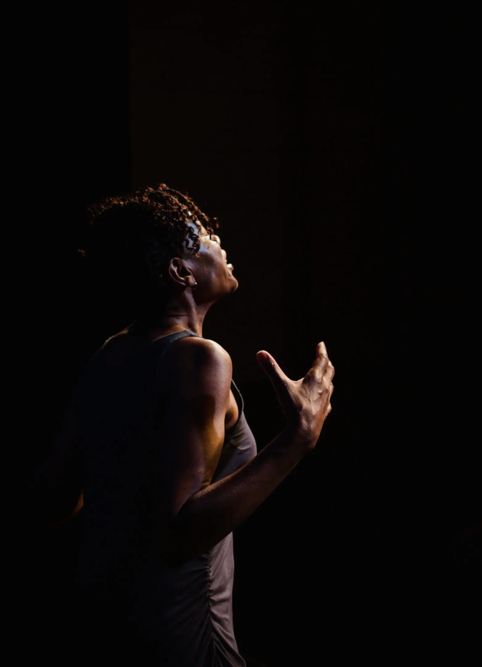 Person passionately performing on dark stage.