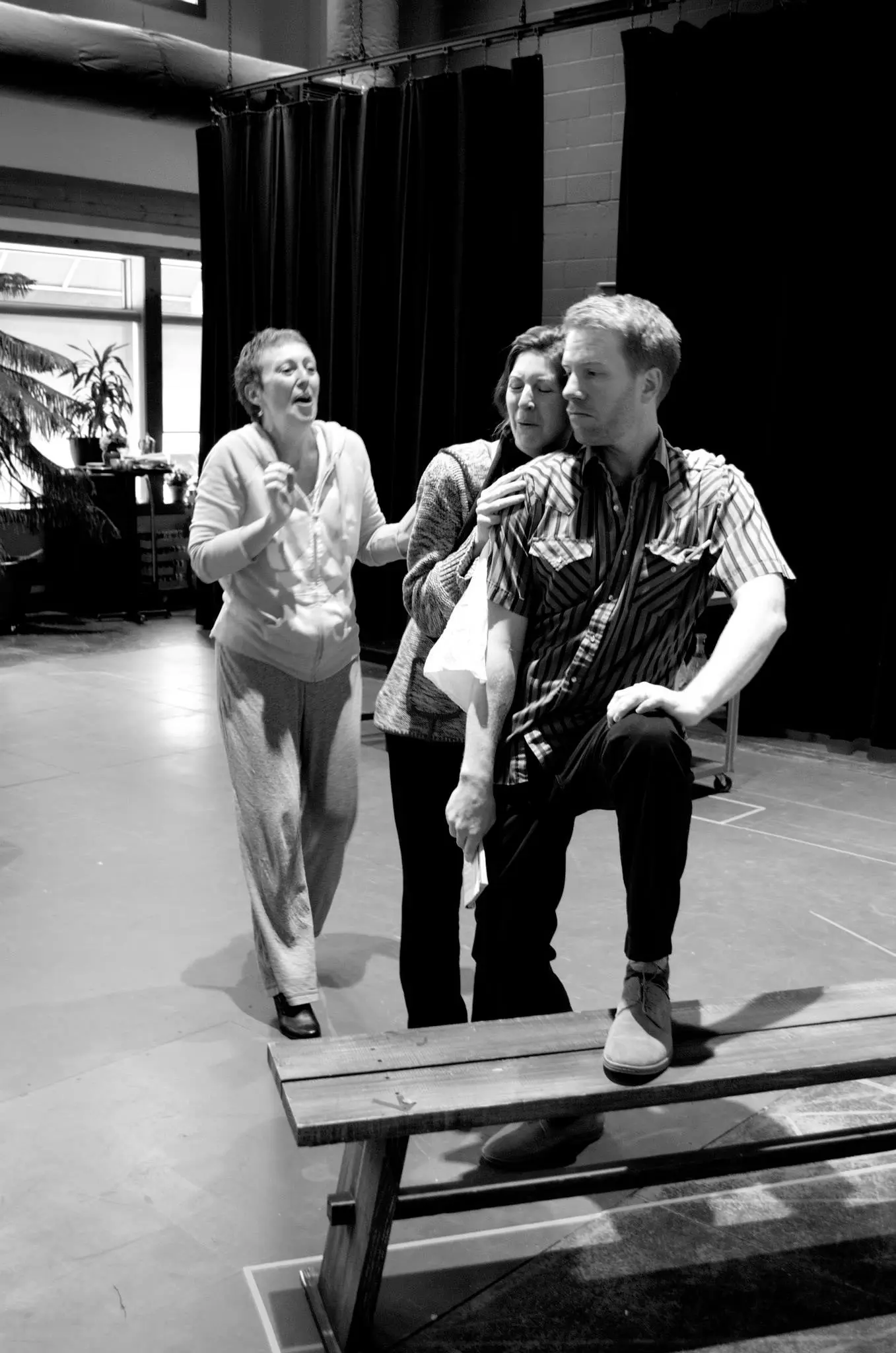Three people rehearsing a scene on stage.