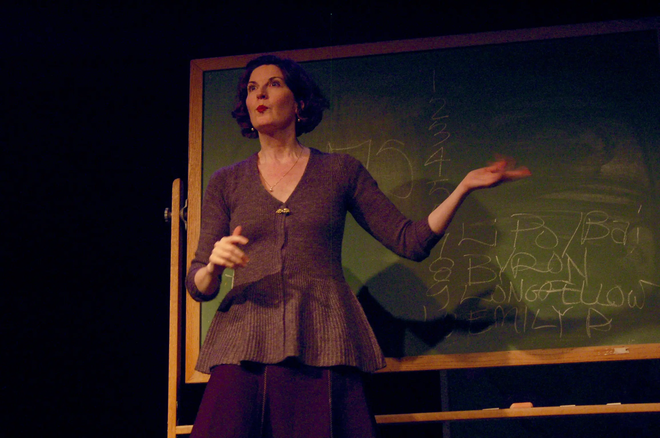 Woman speaking in front of chalkboard.