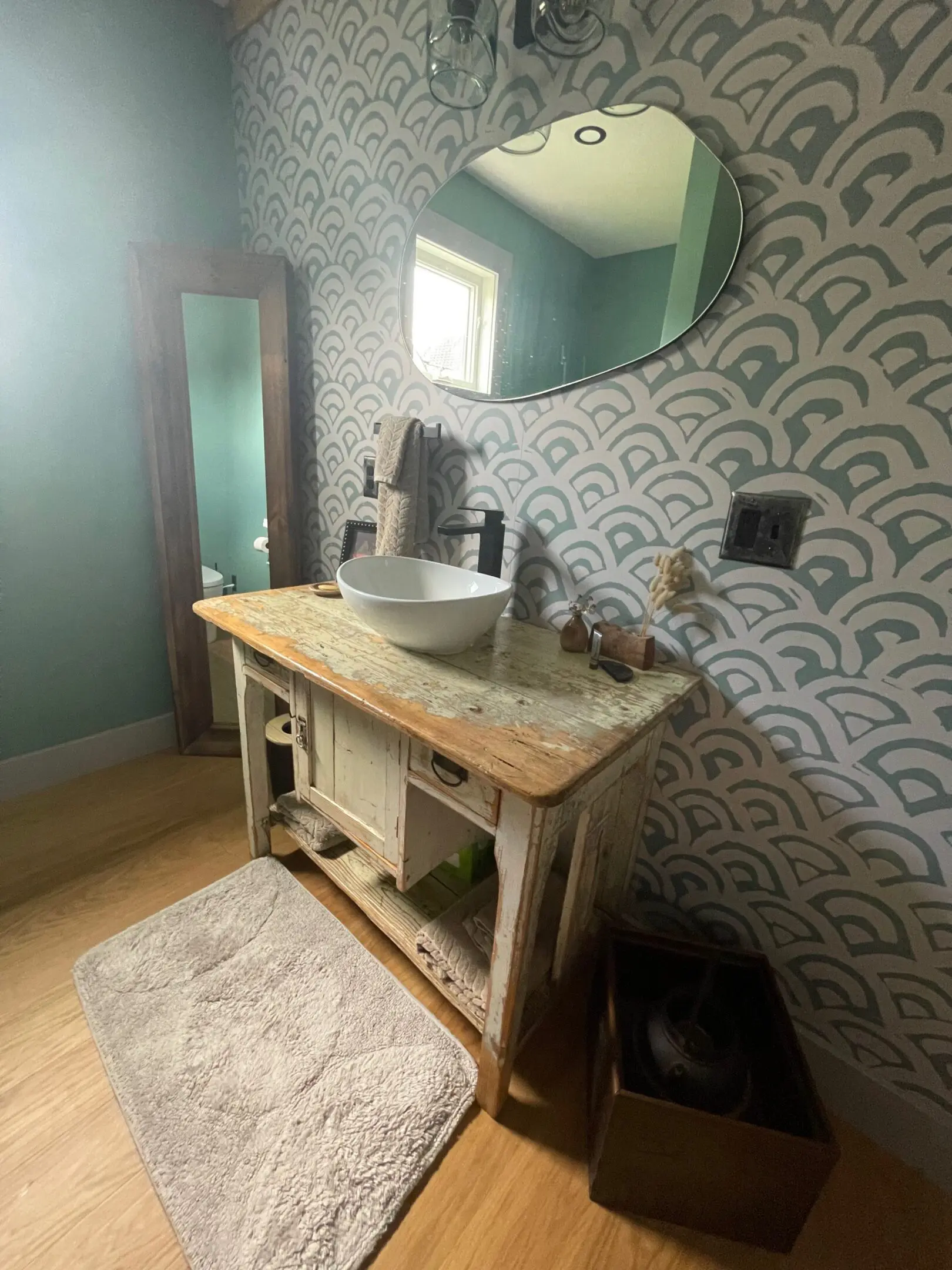 Rustic bathroom vanity with patterned wallpaper.