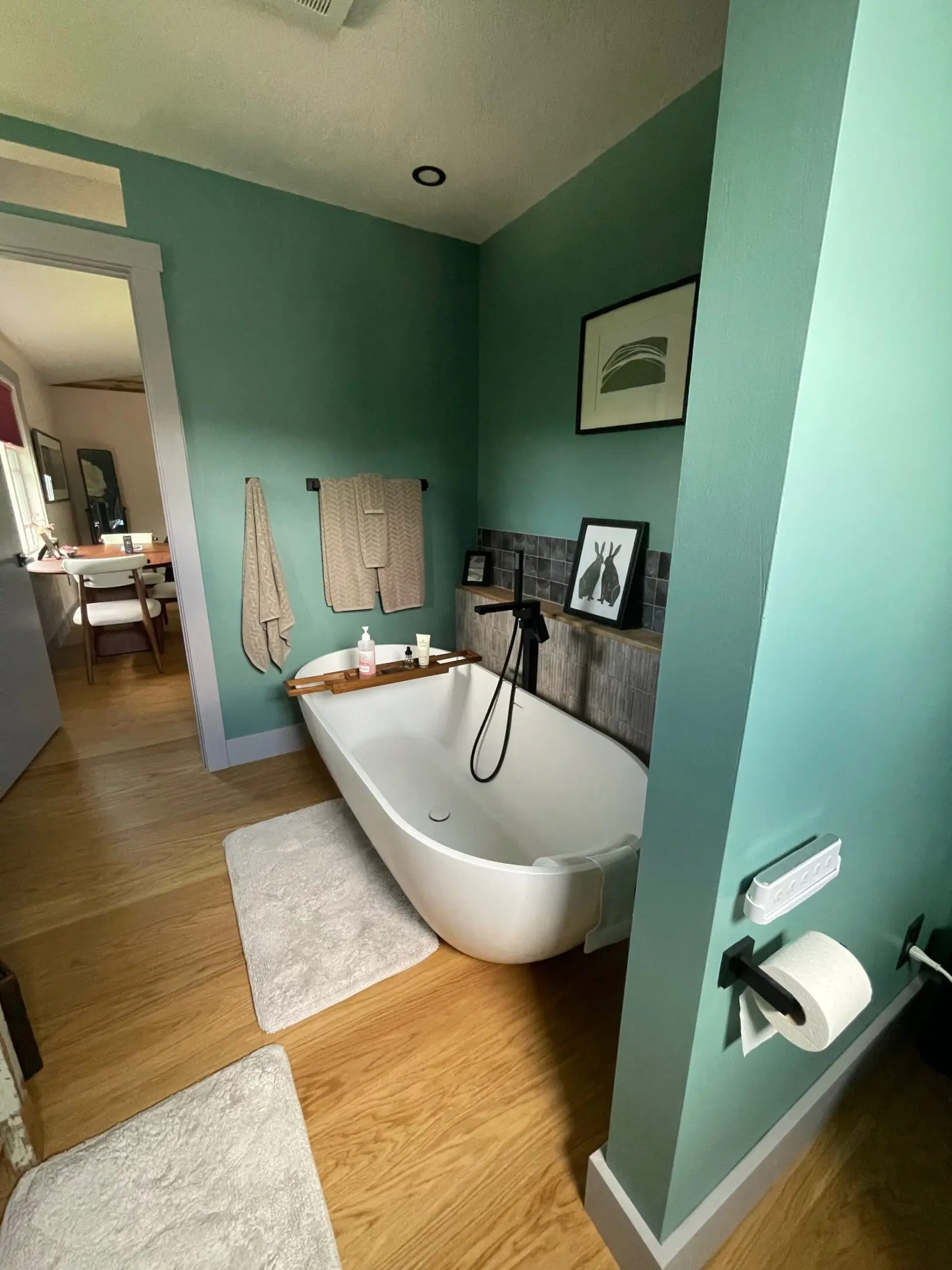 Modern bathroom with freestanding bathtub and artwork.