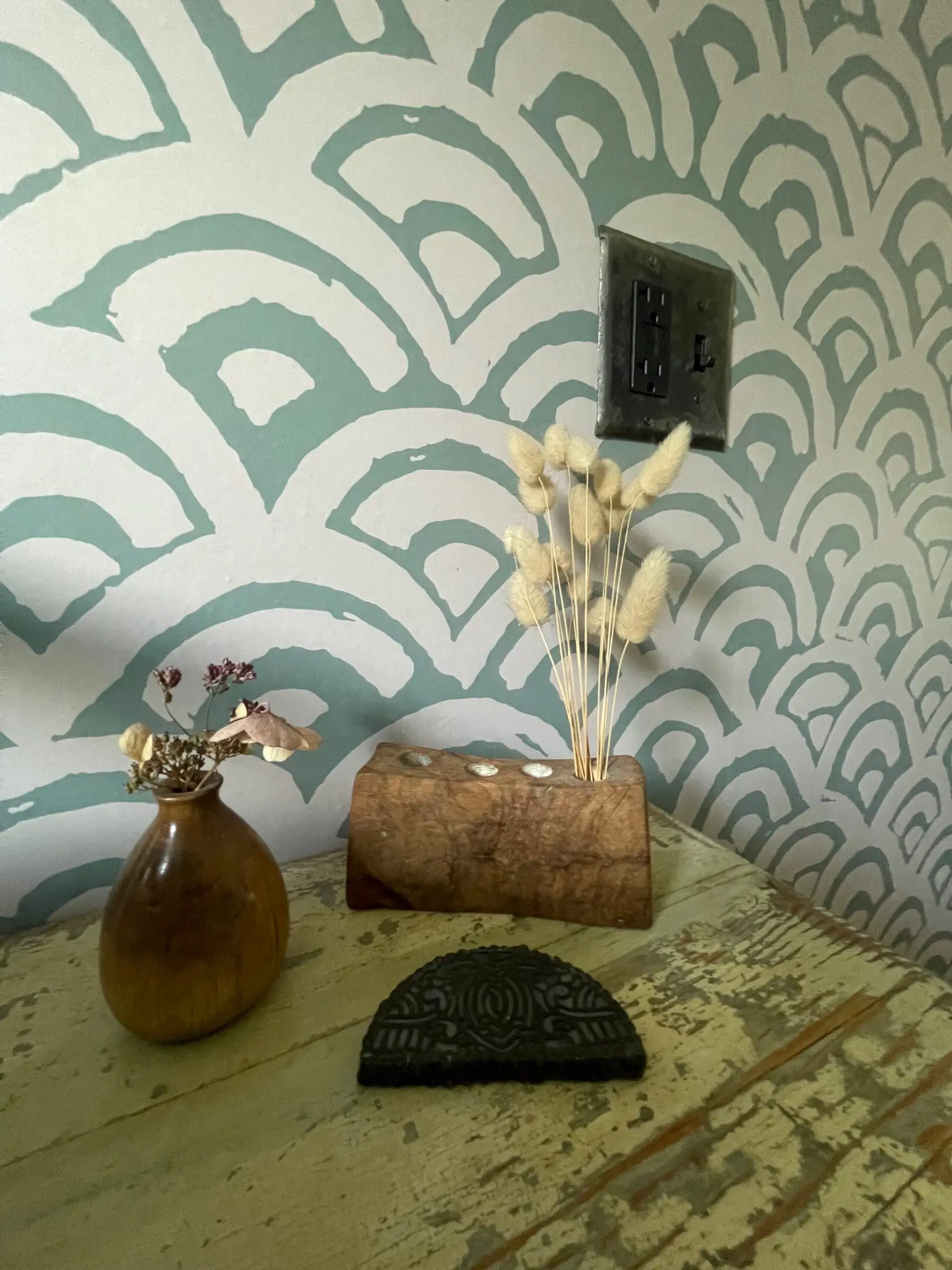 Decorative vases on table with patterned wallpaper.