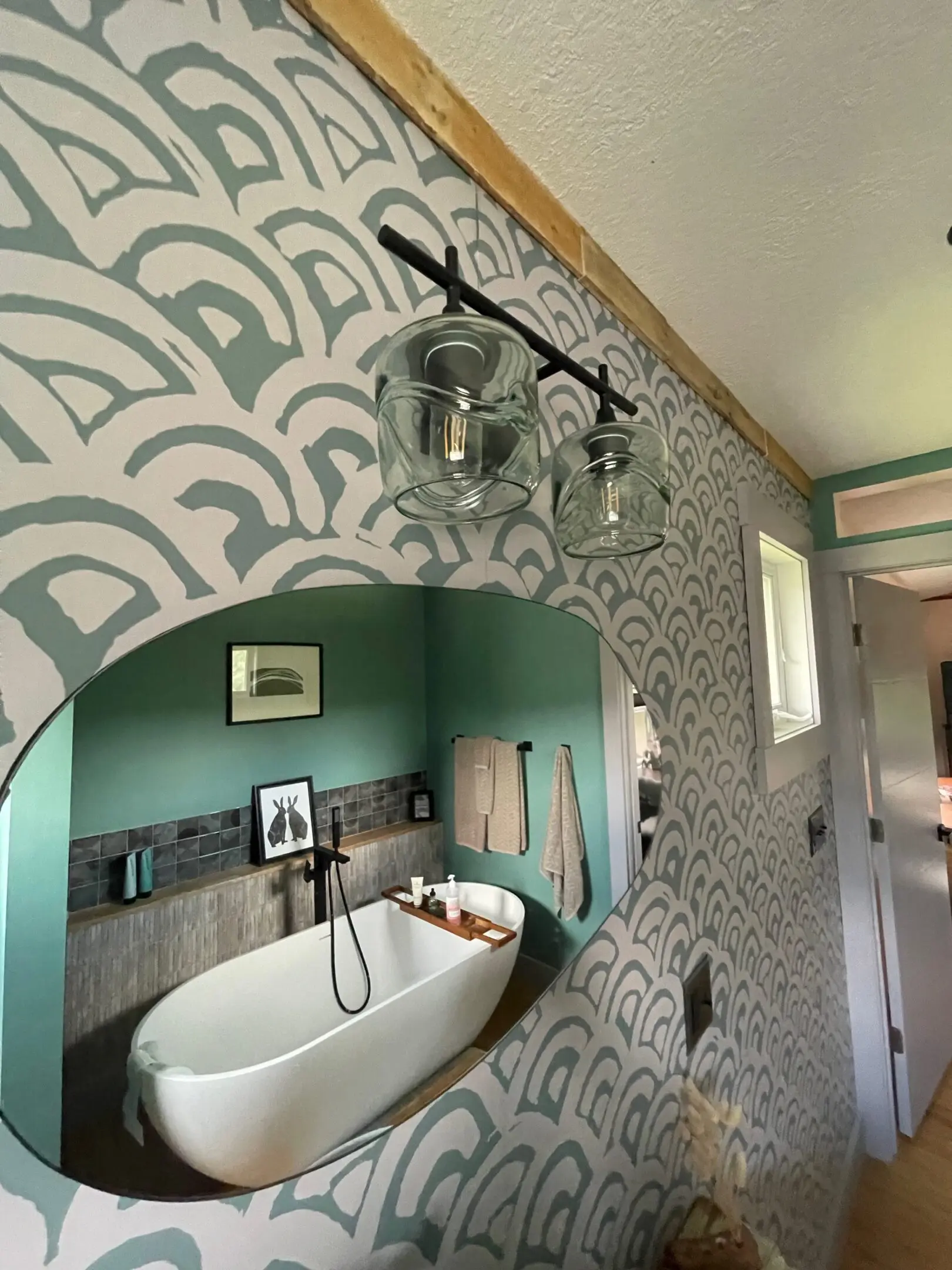 Bathroom with patterned walls and oval mirror.