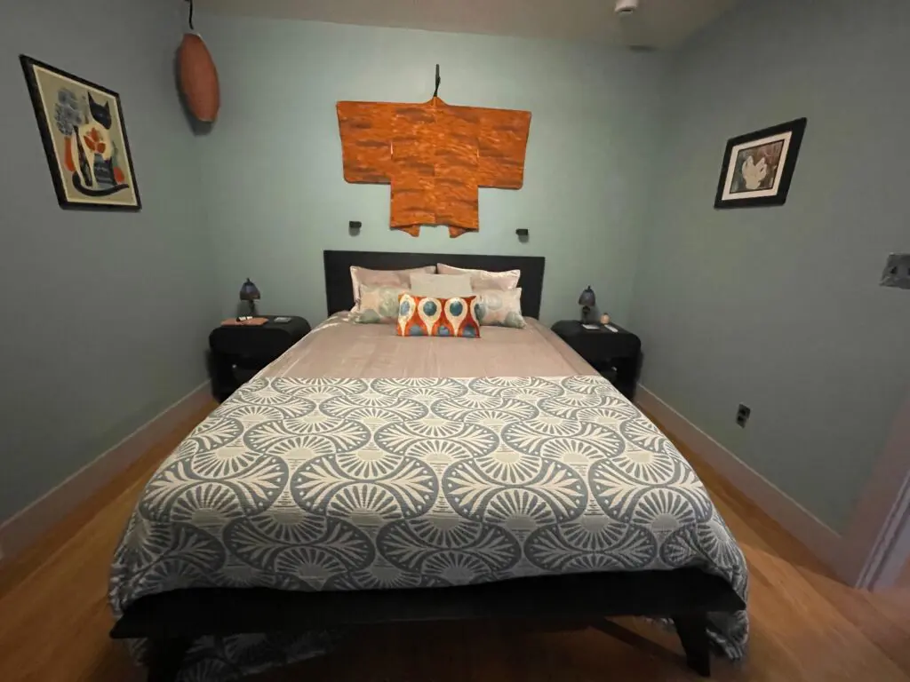Cozy bedroom with patterned bedspread and art.