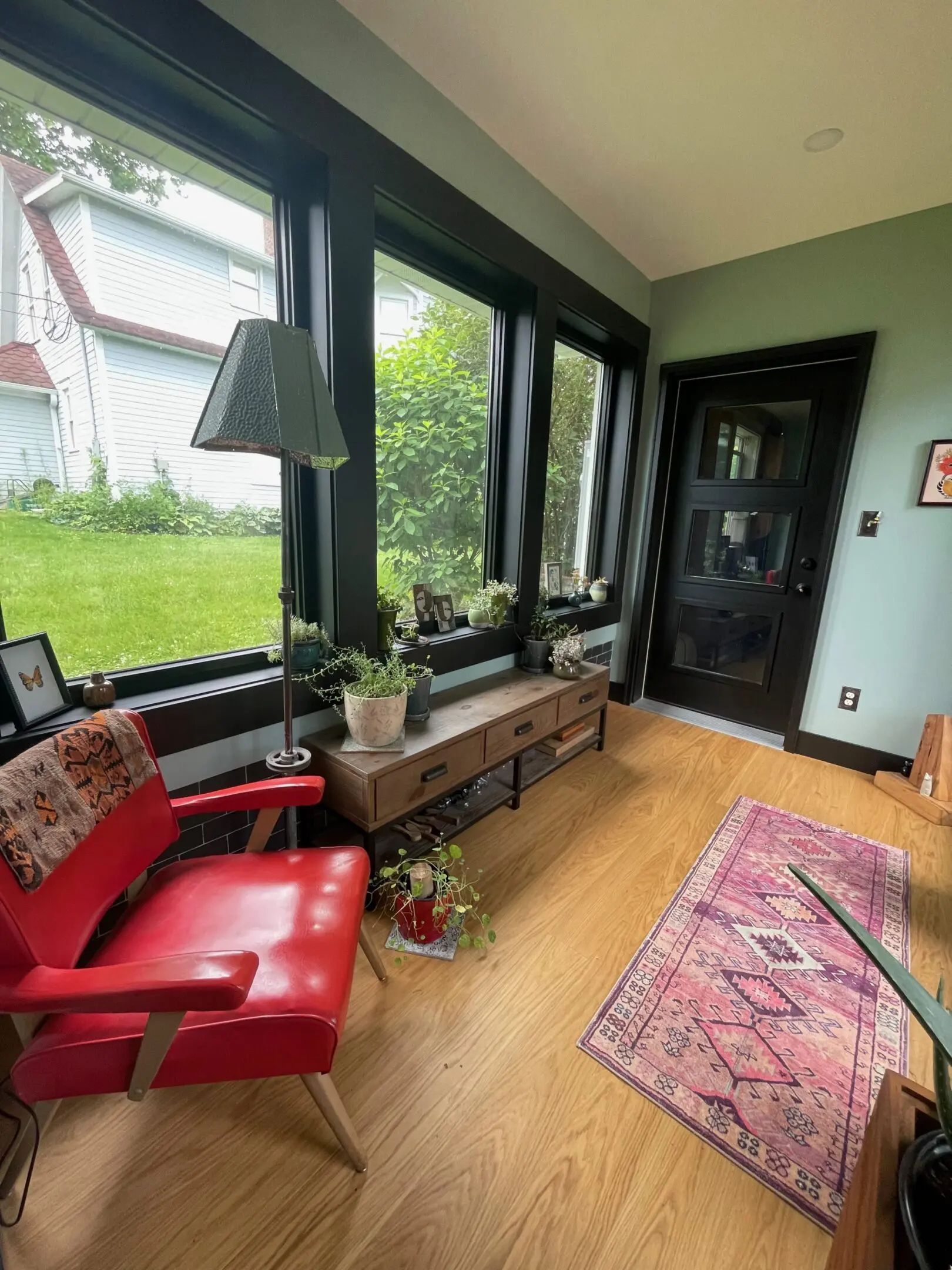 Cozy sunroom with red chair and rug.