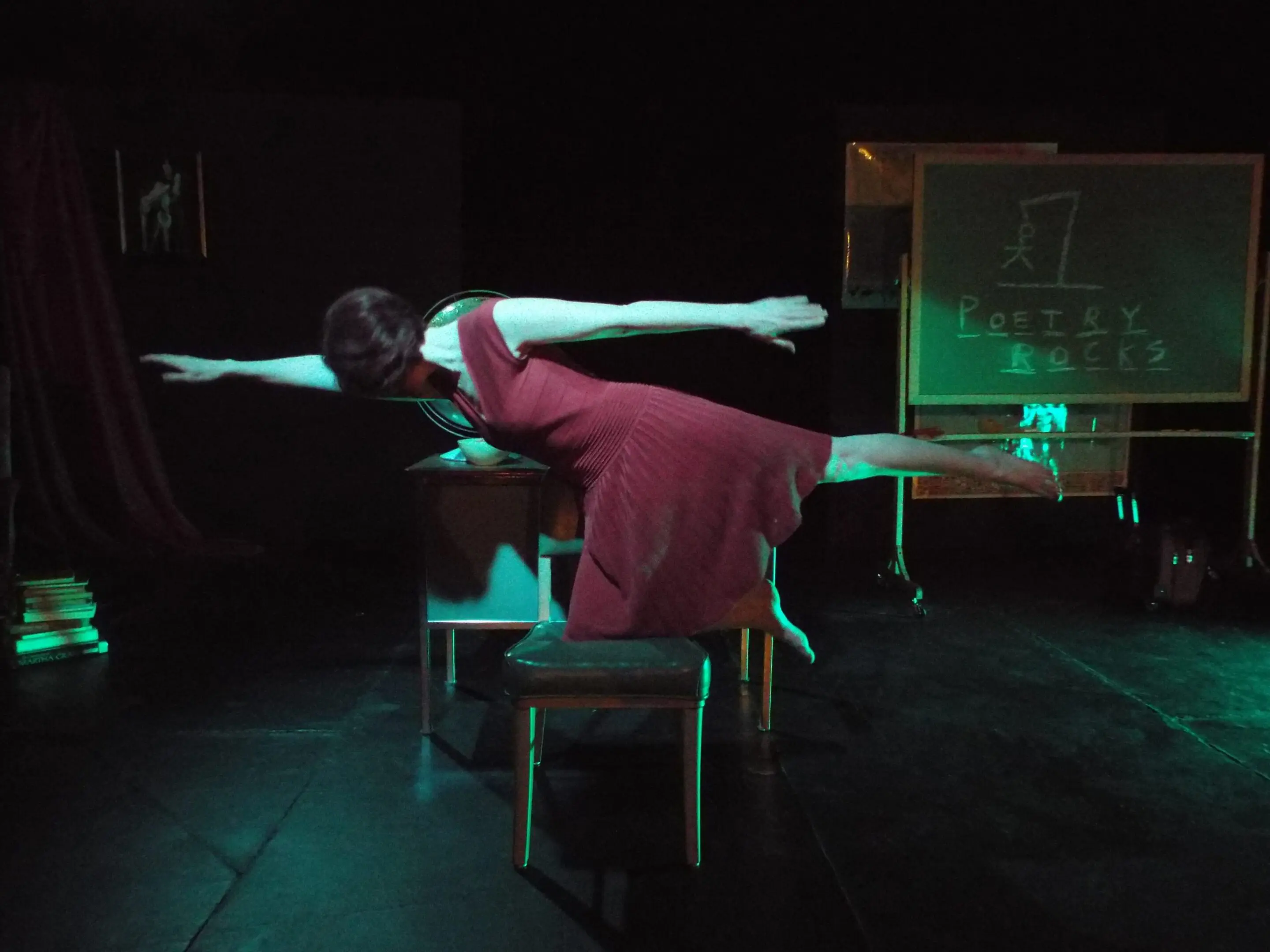 Person balancing on chair in dim lighting.