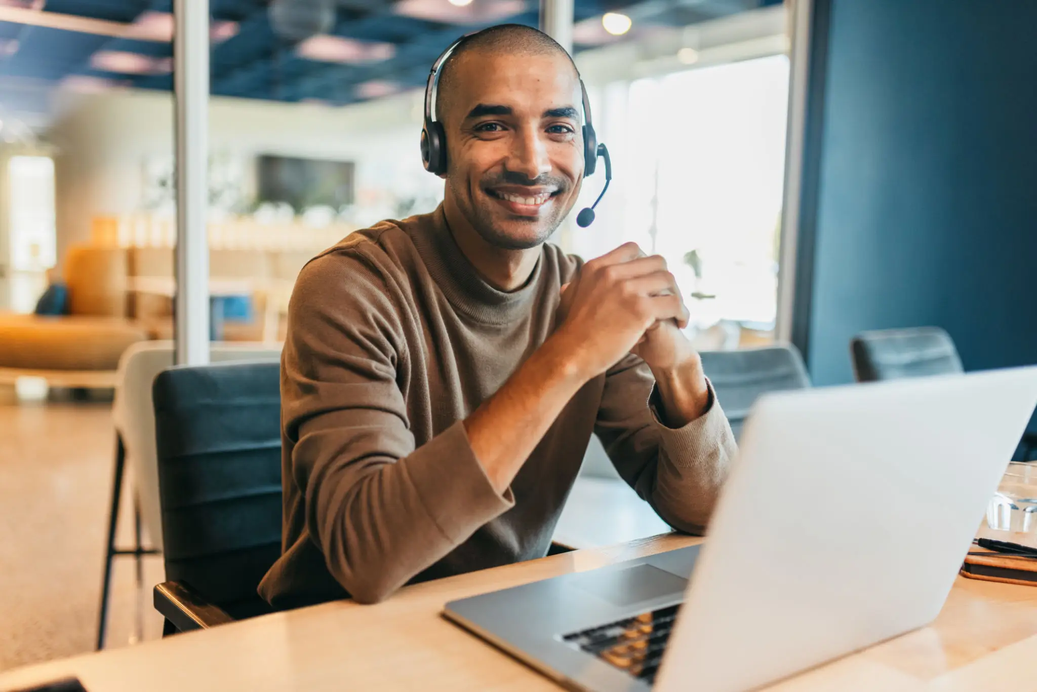 Smiling person with headset using laptop.