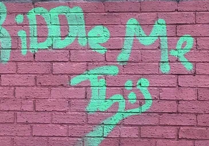 Riddle Me This" spray-painted on wall