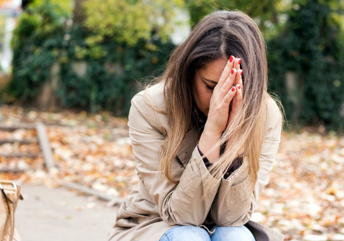 Woman sitting outdoors with hands together