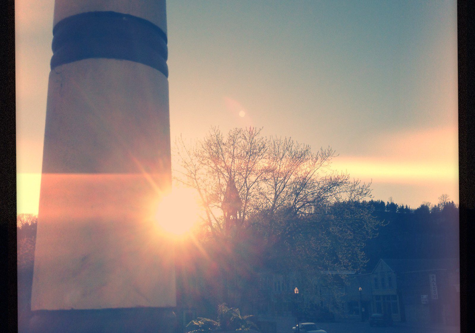 Sunset behind striped pole and tree