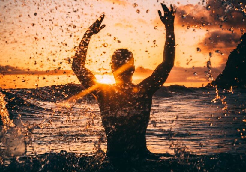 Person enjoying ocean waves at sunset