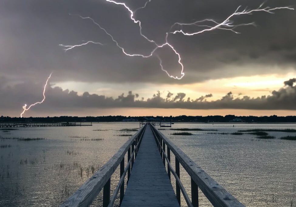 Lightning over wooden pier at sunset